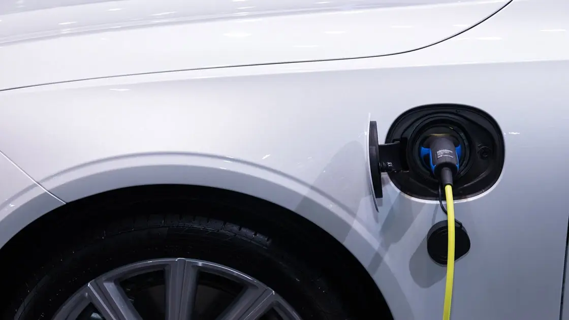 closeup to a white electric vehicle with plugged cable