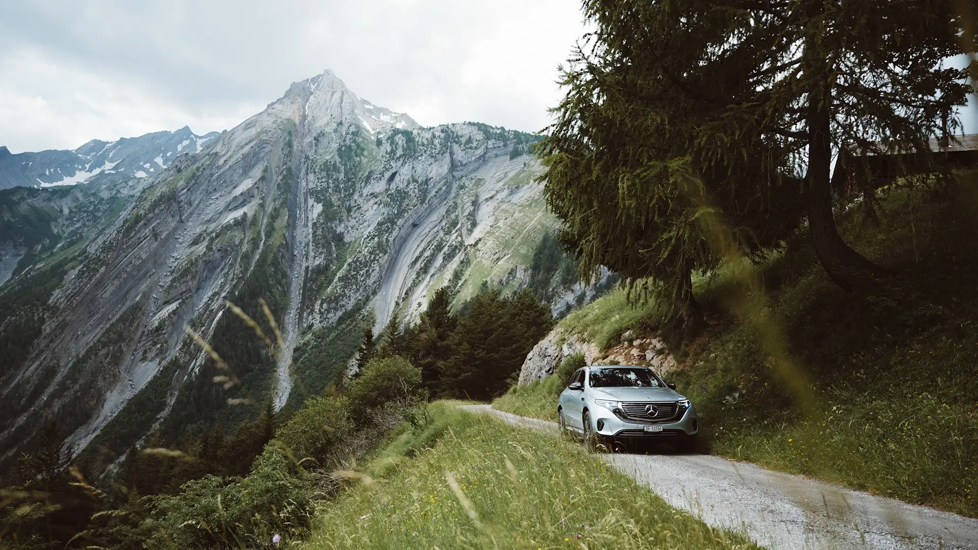E-Auto fährt auf Straße in den Alpen mit Berg im Hintergrund