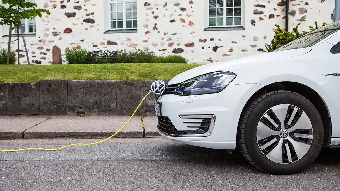 White electric car plugged to a cable in the street