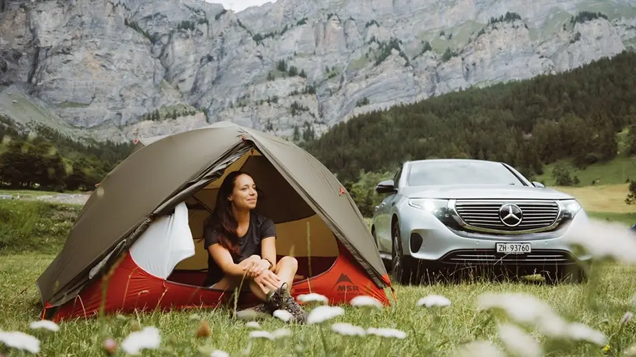 woman sitting in the tent in nature with a grey mercedes car