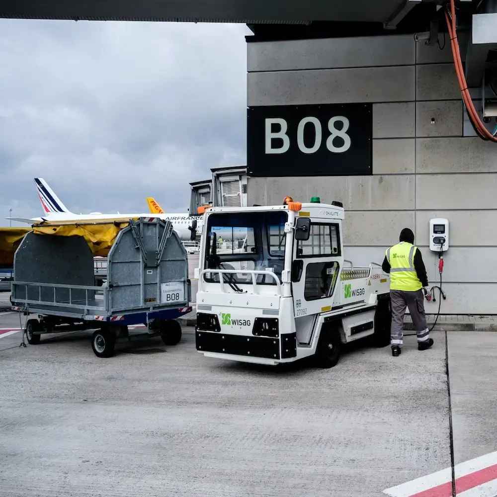 Anställd bredvid elfordon som laddas vid en AC-laddare från Virta på flygplatssidan på BER Berlin Brandenburg Airport