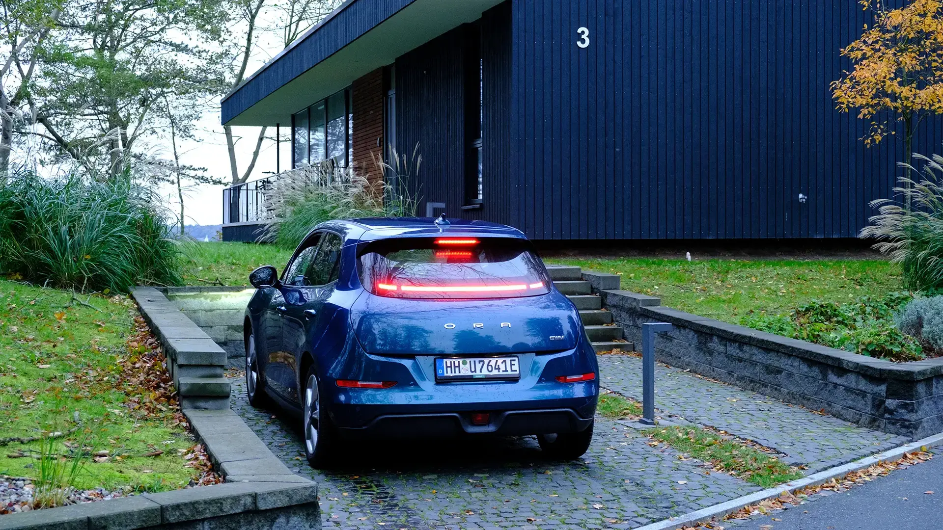 Blaues E-Auto steht vor Lodge geparkt hotel