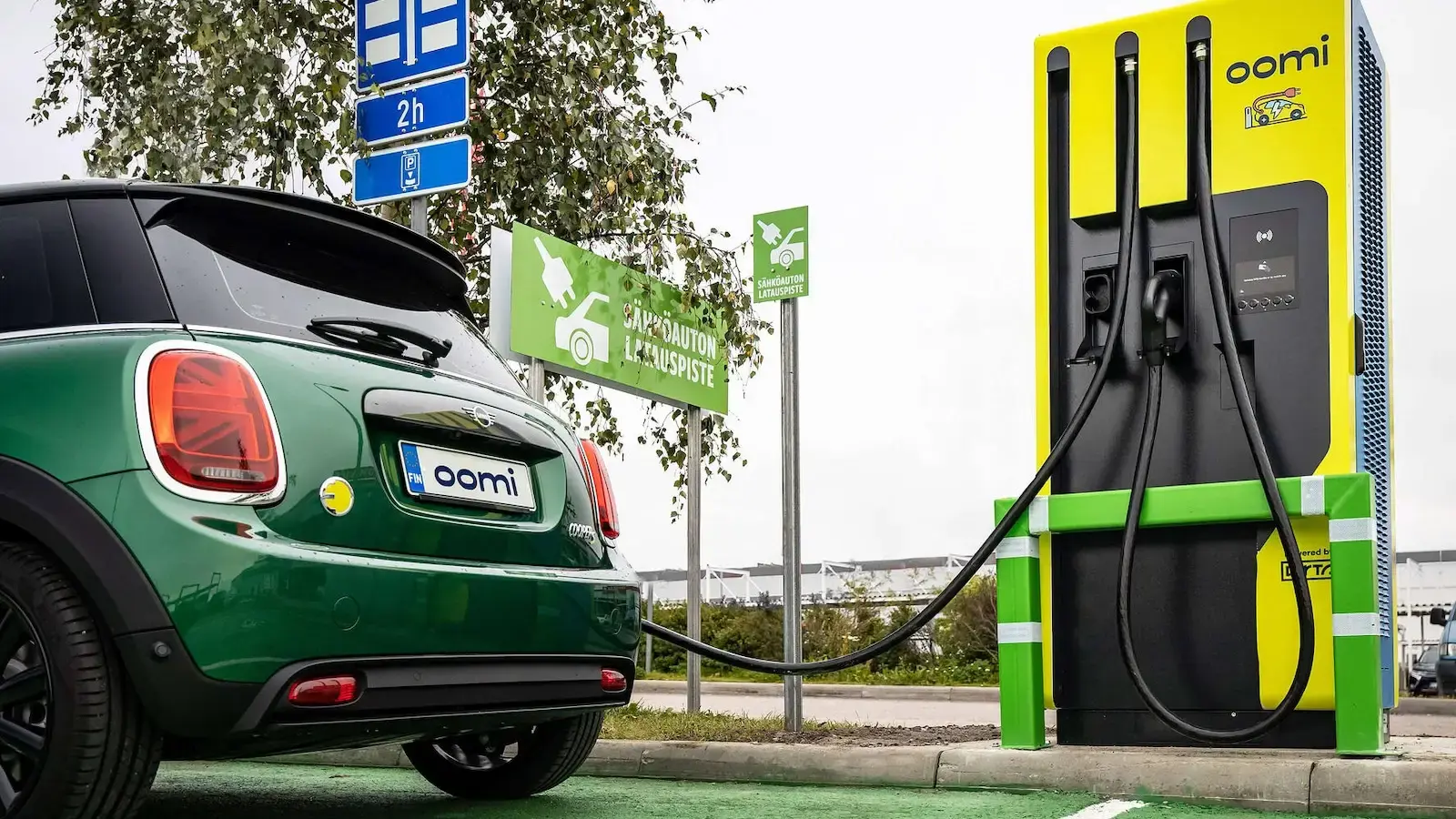 Mini E-Auto lädt an einer oomi Ladestation auf einem Parkplatz in Finnland