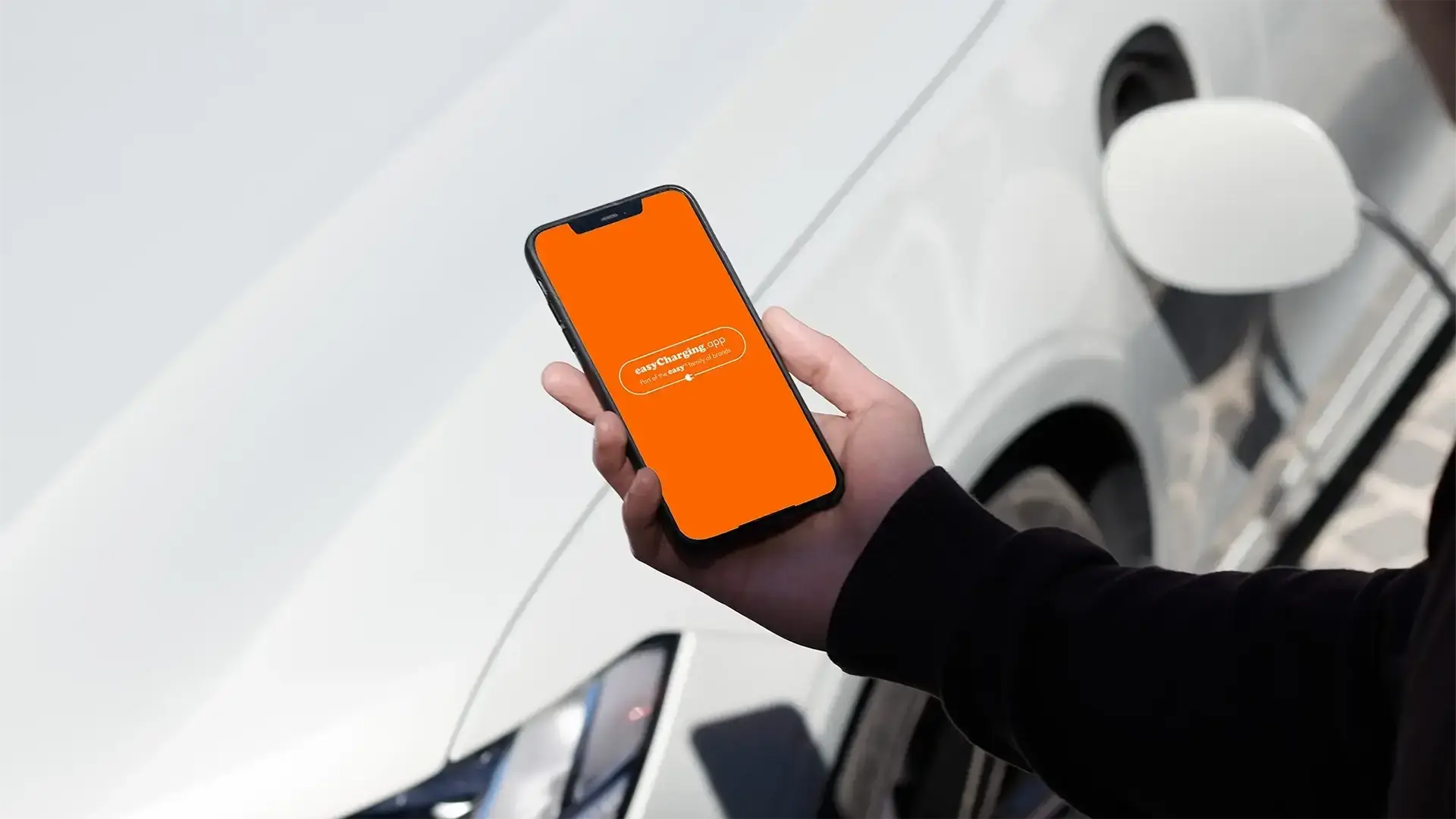 easy-charging-phone-in-hand-in-front-of-white-car