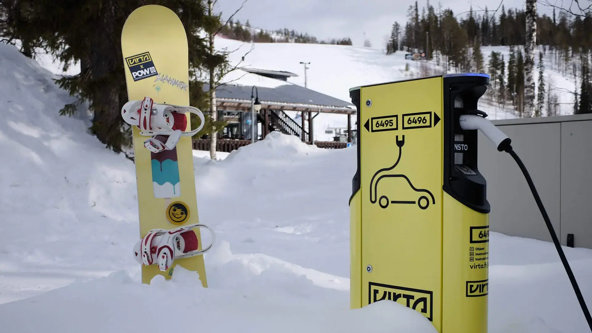 Yellow EV charger and snowboard in snow