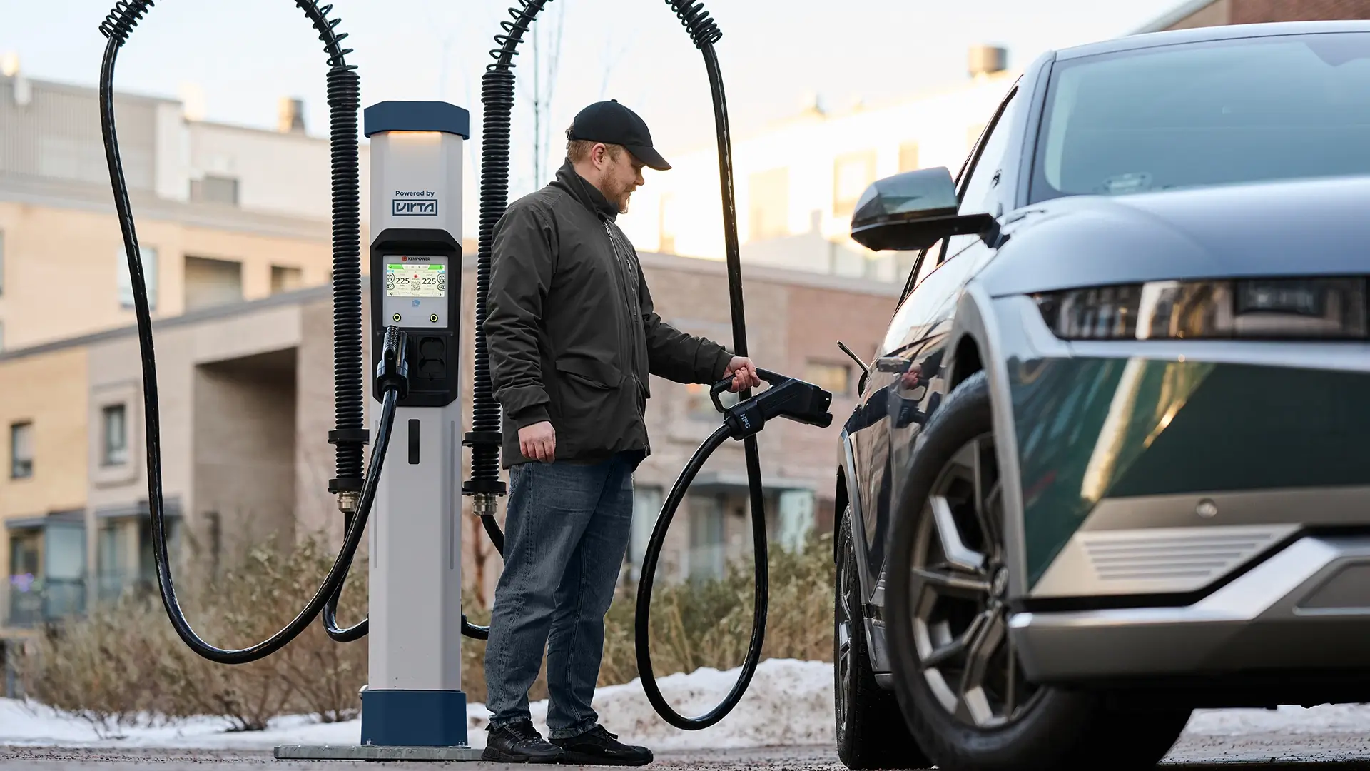 man-using-EV-fast-DC-charging-station-next-to-car